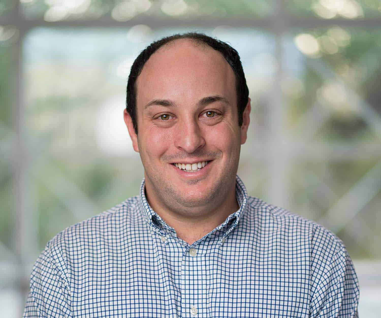 Dr. Friedman Headshot of Dr. Eric Friedman, MD, sports medicine physician at Charleston Sports Medicine, smiling in a blue check dress shirt