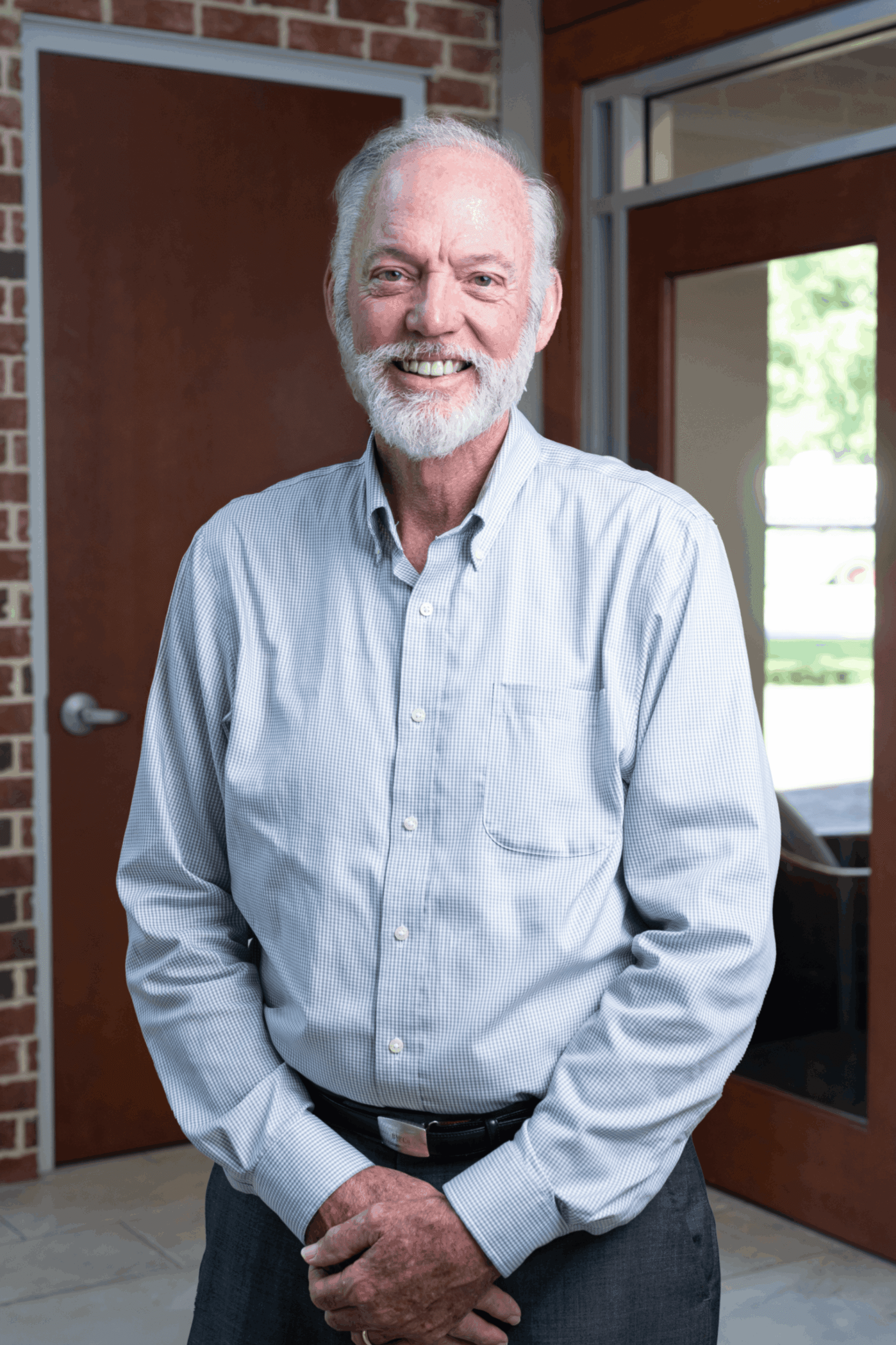 10DR MCCONNELL HEADSHOT (1) (1) Headshot of Dr. Bright McConnell III, MD, founding physician of Charleston Sports Medicine, smiling in a light blue check shirt outside a brick building