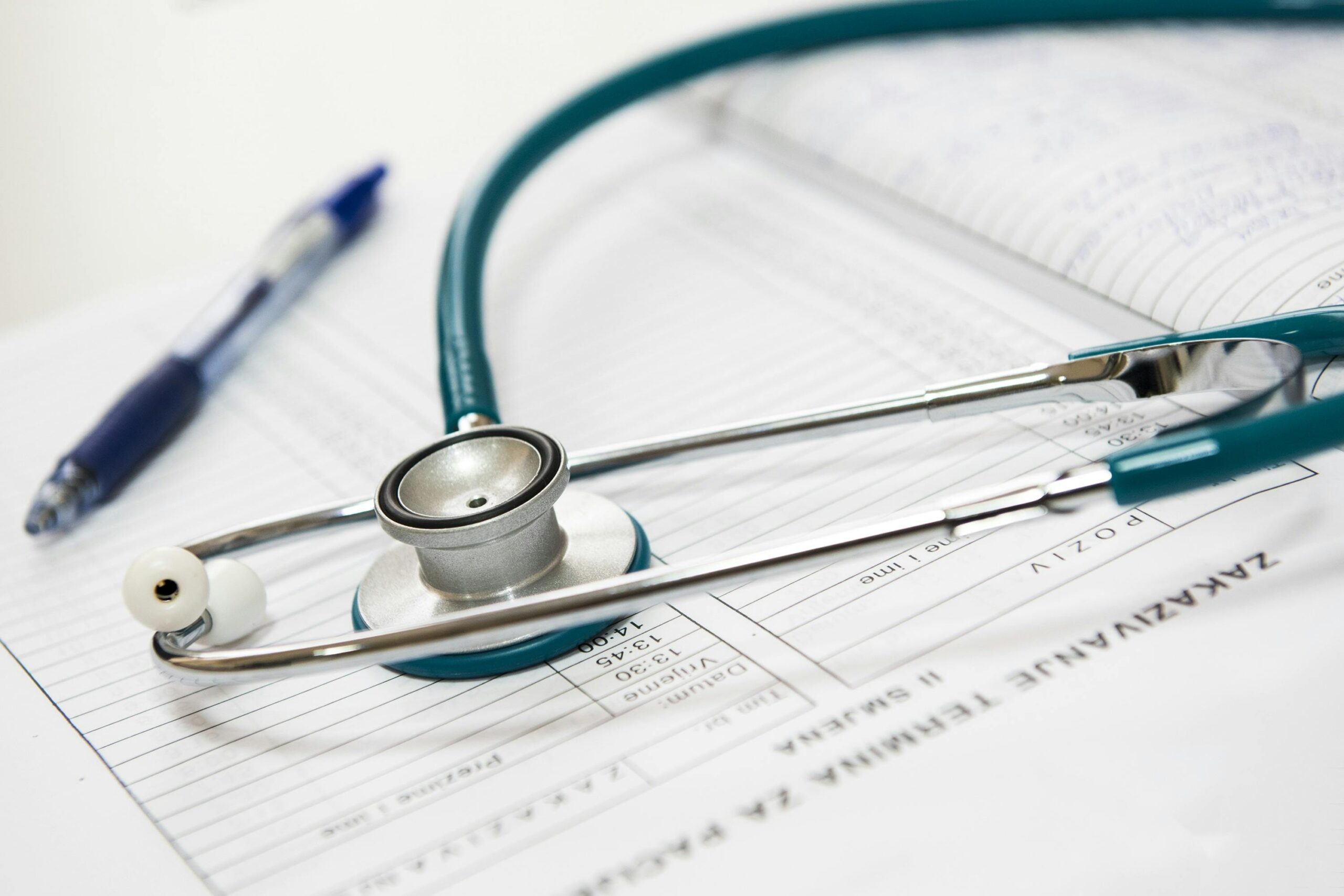 2RapidAppointments Teal stethoscope resting on a medical appointment scheduling form with a pen beside it