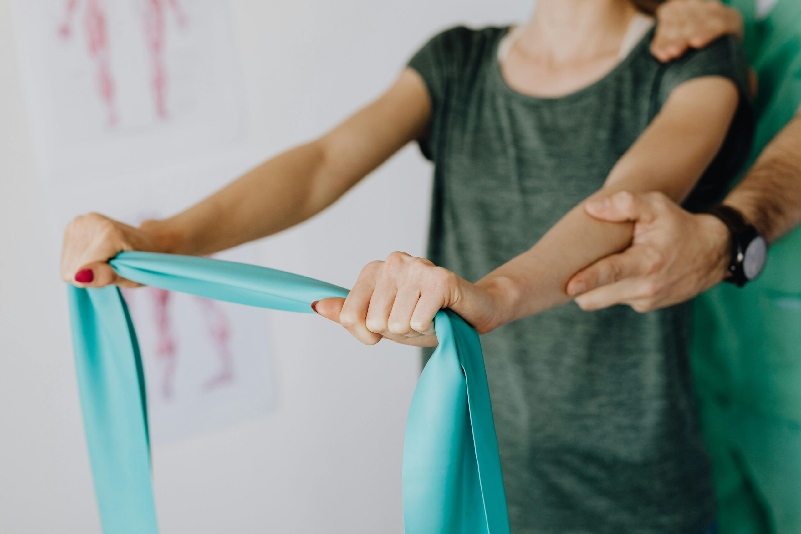 3NonSurgicalFirst Physical therapist guiding a patient's hands as she stretches with a resistance band during a rehabilitation session